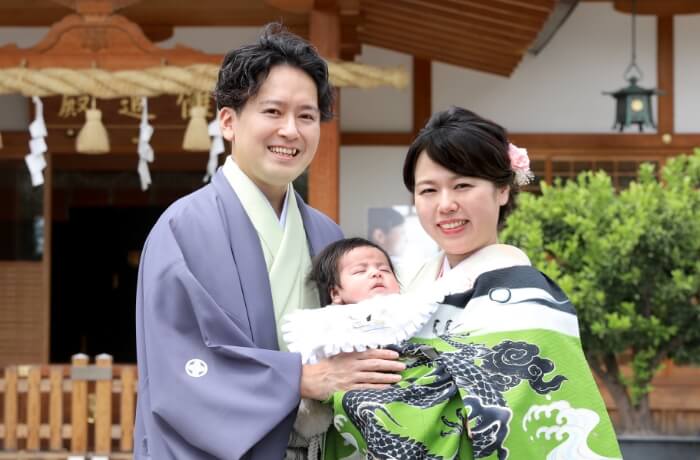  お宮参りロケフォトプランの撮影で笑顔で赤ちゃんを抱っこしているご家族の写真