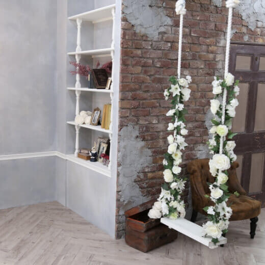 レンガ調の壁とお花のツルが巻き付けられたブランコがあるスタジオ