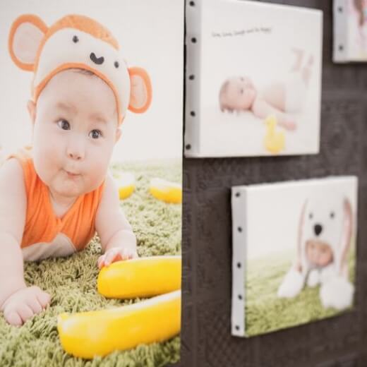 可愛い動物の衣装を着た赤ちゃんの写真が壁に飾られている風景
