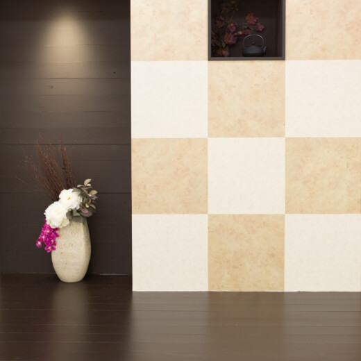 濃いブラウンの床に、白色とクリーム色のブロックチェック柄の壁がある空間にお花が生けられているスタジオ