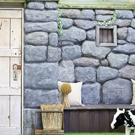石の壁と干し草がある空間に、牛のオブジェクトが置いてあるスタジオ