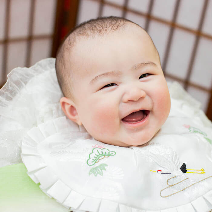 お宮参りスタジオフォト撮影で祝い着の上で満面の笑みを浮かべる赤ちゃんの写真